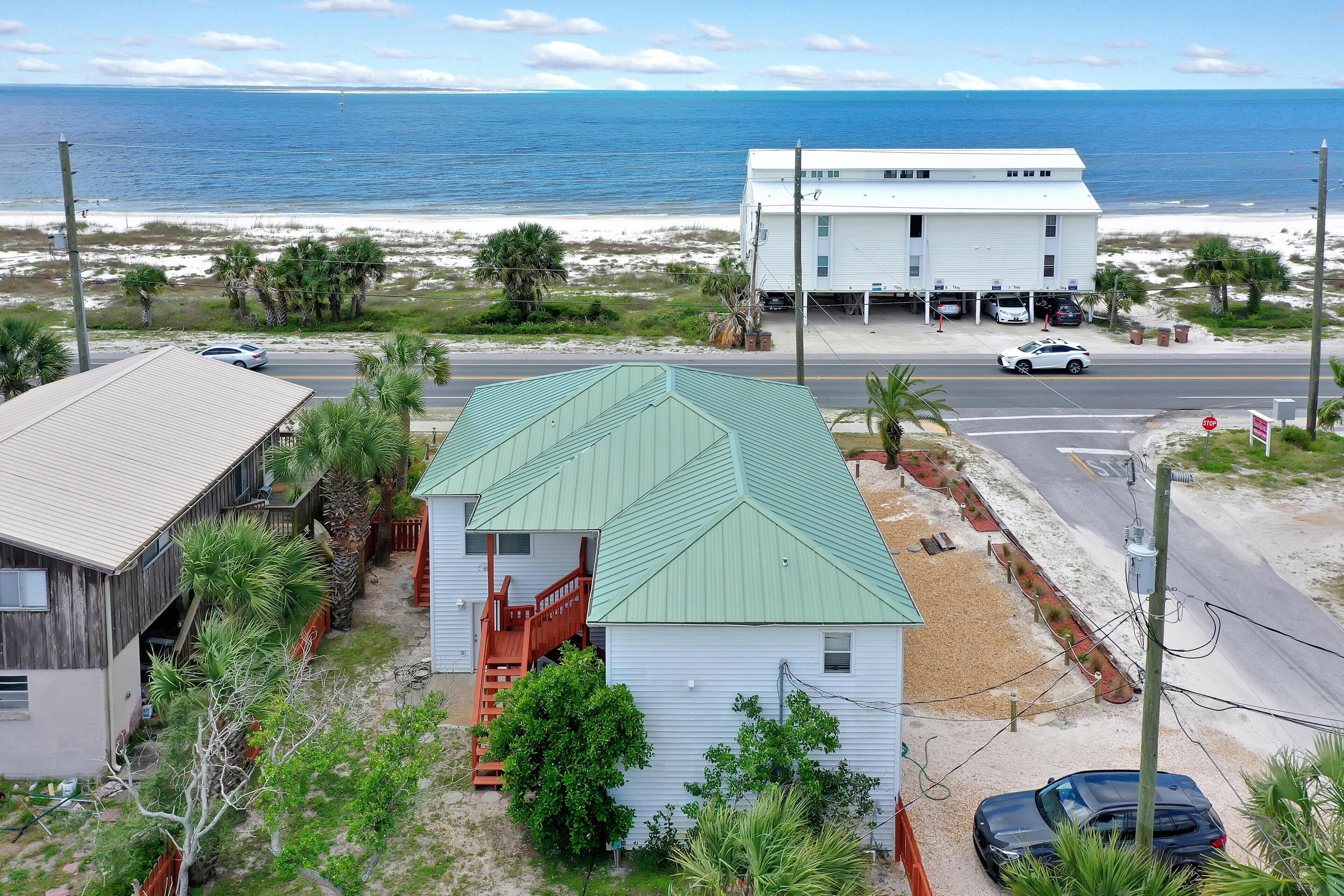 A coastal property with a white building, a garage, and a road leading to the beach.