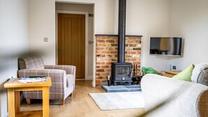 A living room with a fireplace, a television, and a sofa. - A family break that sleeps 4 guests  in 2 bedrooms (York)