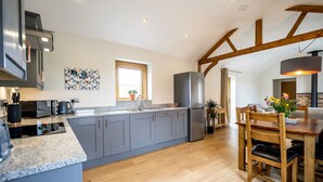 A modern kitchen with grey cabinets, a stainless steel refrigerator, and a wooden dining table with chairs. - A family break that sleeps 4 guests  in 2 bedrooms (York)