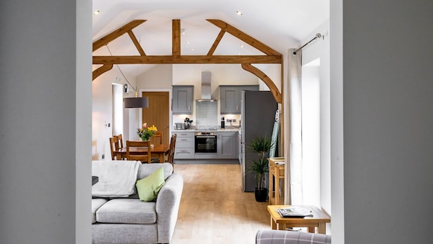 A modern kitchen with grey cabinets, a central island, and wooden beams on the ceiling. - A family break that sleeps 4 guests  in 2 bedrooms (York)