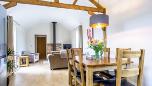 A spacious living area with a wooden dining table, chairs, and a modern pendant light. A sofa and a small wooden table are also visible. - A family break that sleeps 4 guests  in 2 bedrooms (York)