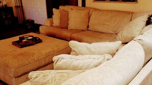 A living room with a beige sofa, a matching ottoman, and several cushions. - Charming, convenient and comfortable!! (Albuquerque)