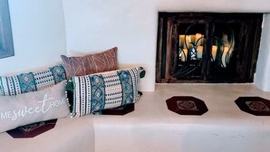 A cozy living room with a fireplace, patterned cushions, and a decorative pillow with text. - Charming, convenient and comfortable!! (Albuquerque)