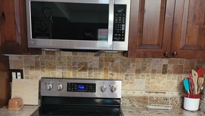 A kitchen with a stainless steel microwave, a black stove, and a tiled backsplash. - Charming, convenient and comfortable!! (Albuquerque)