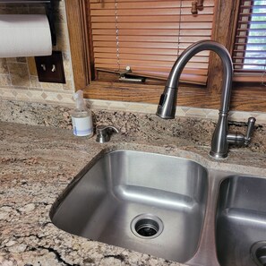 A kitchen sink with a faucet, a soap dispenser, and a window with blinds. - Charming, convenient and comfortable!! (Albuquerque)