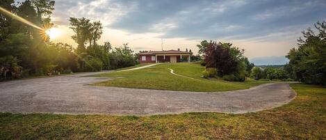 A house with a driveway leading to a garage, surrounded by a well-maintained lawn and trees.