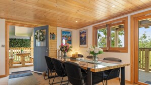 Un intérieur en bois comprenant un coin repas, une porte ornée d’une guirlande et des tableaux encadrés accrochés au mur.