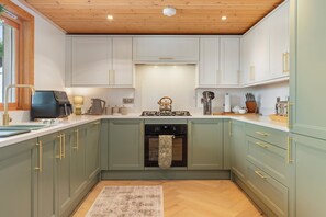 A kitchen with light green cabinets, a central island, and a wooden ceiling.
