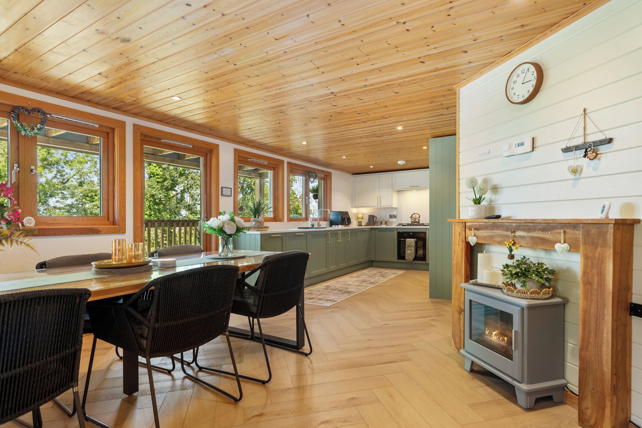 A spacious kitchen with wooden beams, a dining area with chairs, and a fireplace.