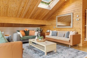 A cozy log cabin interior with a high ceiling, a skylight, a large mirror, and a fireplace.