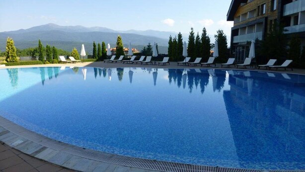 A clear swimming pool with lounge chairs and a mountain view in the background. - 1 Bed - Sleeps 4 - Pets - Mountain Views (Razlog)