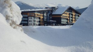 A modern building with multiple floors and a ski lift in the background, surrounded by snow and mountains. - 1 Bed - Sleeps 4 - Pets - Mountain Views (Razlog)