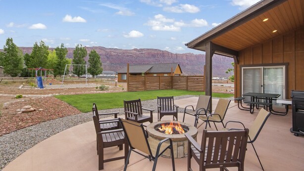 Une terrasse extérieure avec un foyer, un barbecue et une vue sur les montagnes.
