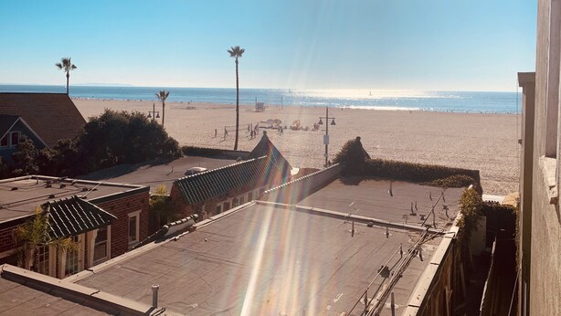 A beach view from a building with a flat roof, palm trees, and a clear sky. - Heavenly Beach-front Apartment in Venice (Los Angeles)