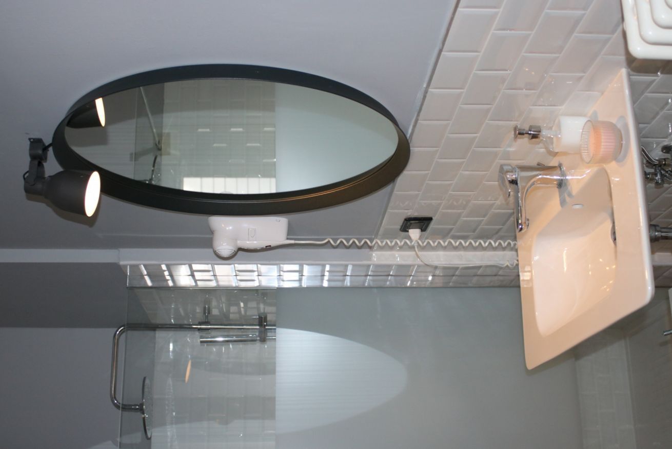 Ein Badezimmer mit rundem Spiegel, Waschbecken und Dusche.