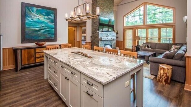 A spacious kitchen with a large island, wooden cabinets, and a stone accent wall.