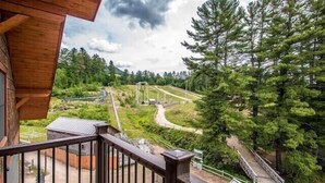 A balcony with a view of a railway track and surrounding greenery.
