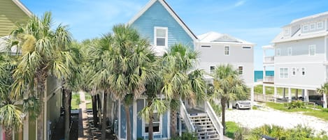 Une zone résidentielle côtière avec une maison bleue, des palmiers et une plage de sable.