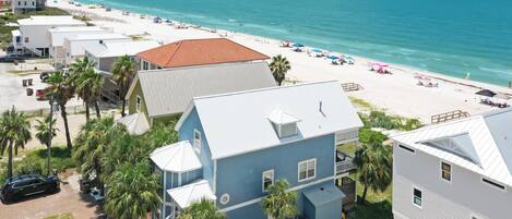 A coastal hotel with multiple buildings, a beach, and a clear view of the ocean.