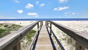A wooden boardwalk leading to a beach with a clear sky. - Bethany Cottage (Port St. Joe)