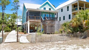 A two-story building with a balcony, a covered porch, and a wooden deck. - Bethany Cottage (Port St. Joe)