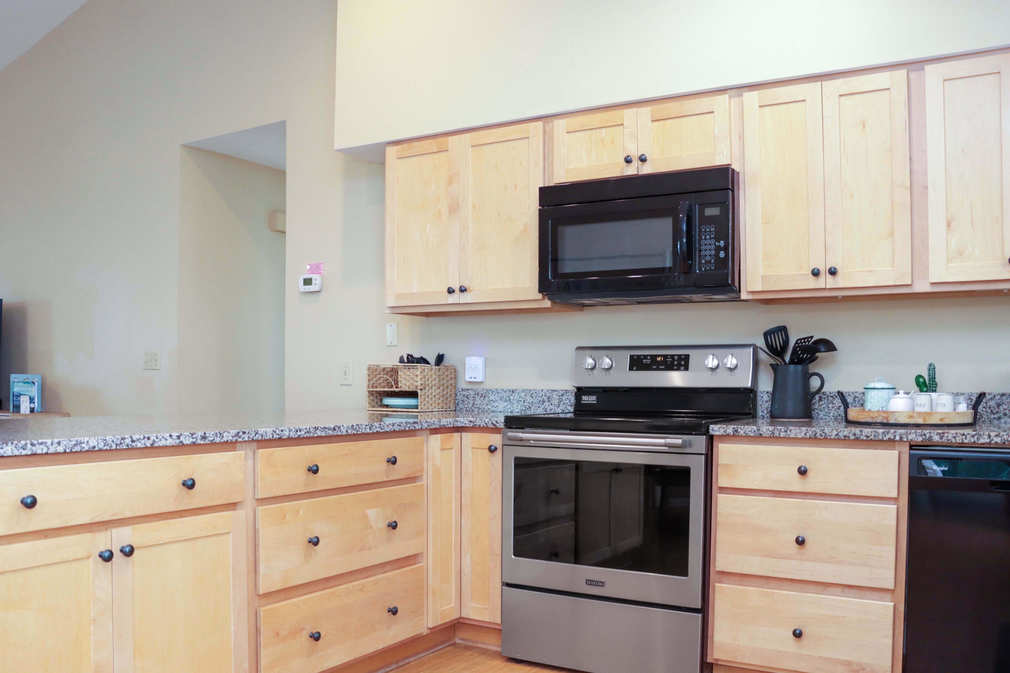 A kitchen with wooden cabinets, a stainless steel oven, a microwave, and a dishwasher.