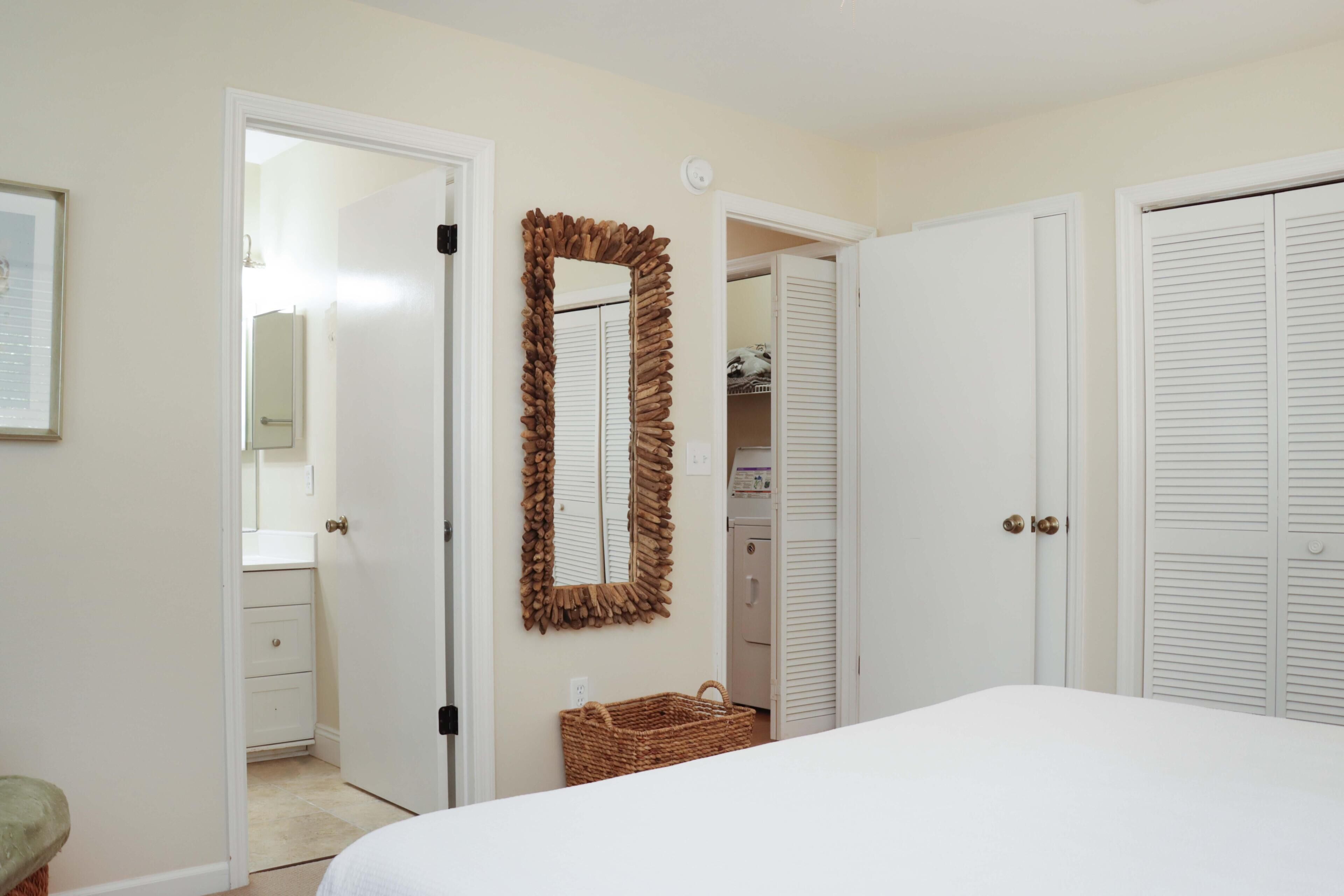 A bedroom with a bed, a mirror, a wardrobe, and a door leading to a bathroom.