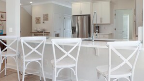 A modern kitchen with white cabinetry, a stainless steel refrigerator, and a chandelier. - Big Chill (Port St. Joe)