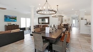 A spacious dining area with a large wooden table, wicker chairs, and a chandelier. - Big Chill (Port St. Joe)