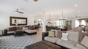 A spacious living room with a large sectional sofa, a patterned rug, and a dining area in the background. - Big Chill (Port St. Joe)
