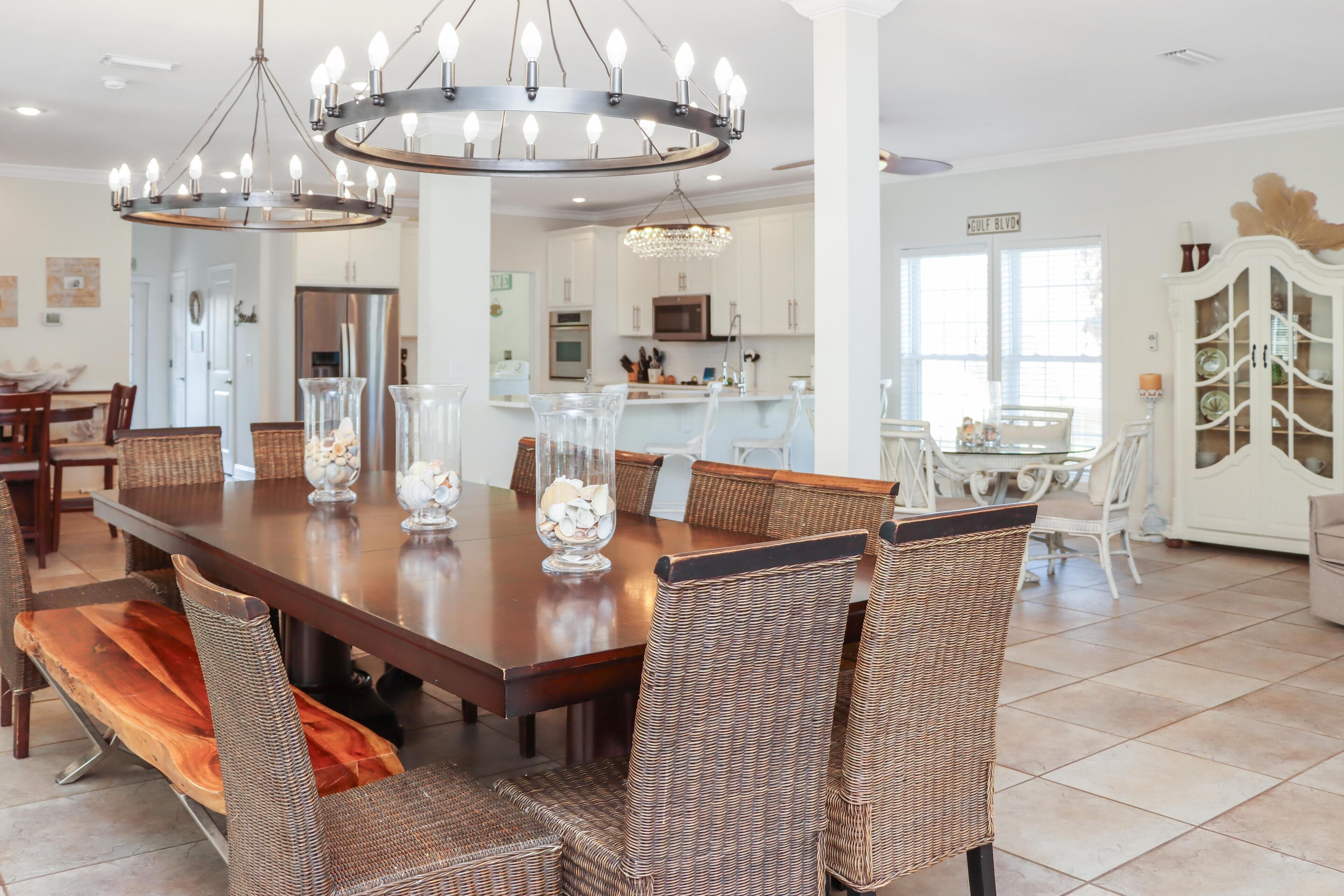 A spacious dining area with a large wooden table, wicker chairs, and a modern chandelier.