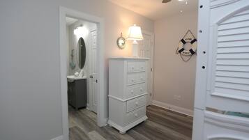 A hallway with a white dresser, a mirror, and a wall-mounted lamp.