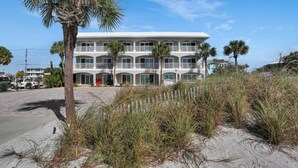 A beachfront hotel with multiple balconies, palm trees, and a sandy beach area. - Beach Destiny (Port St. Joe)