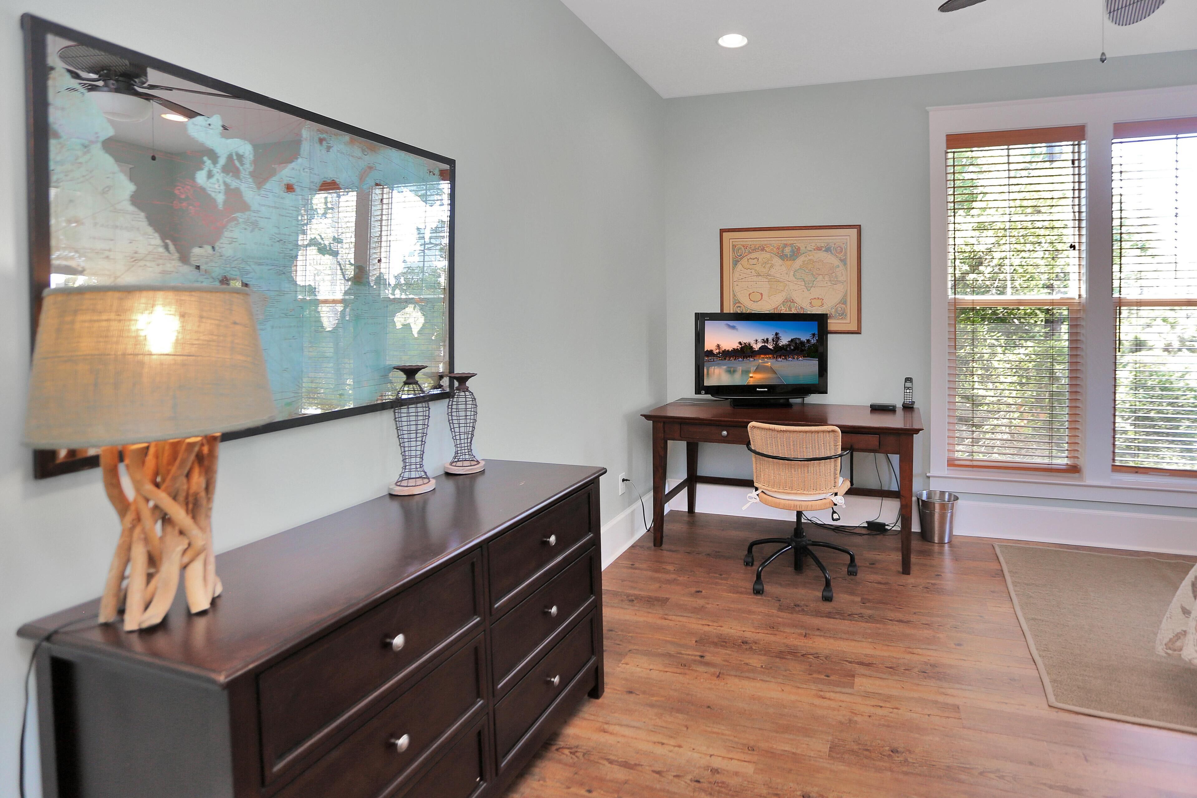A room with a wooden desk, a computer, a chair, a large mirror, and a map on the wall.