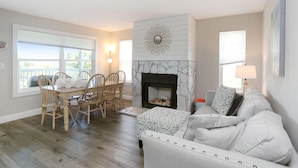 A living room with a fireplace, a dining area with chairs, and a sofa. - Buckeye Beach House (Port St. Joe)