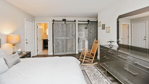 A bedroom with a bed, a dresser, a rocking chair, and a sliding door closet. - Buckeye Beach House (Port St. Joe)