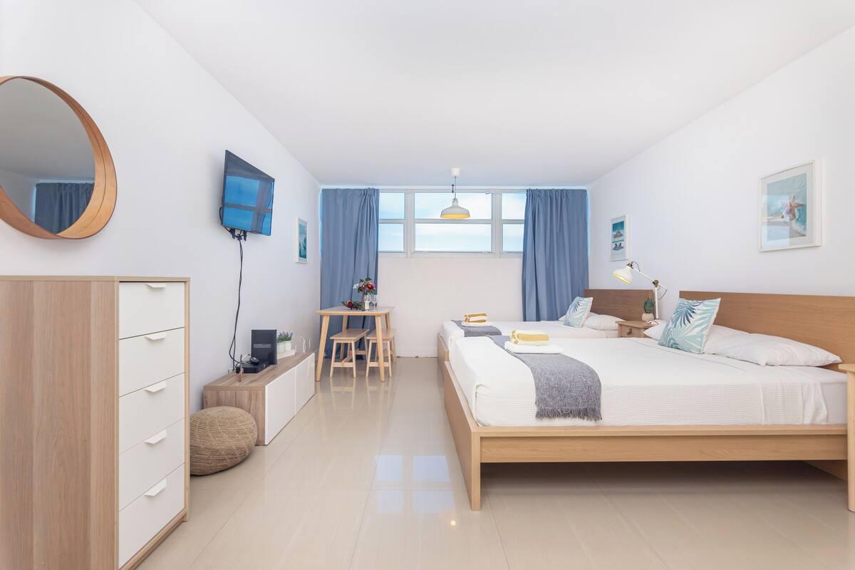 Quarto moderno com cama de madeira, escrivaninha, cadeira, guarda-roupa e um espelho grande.