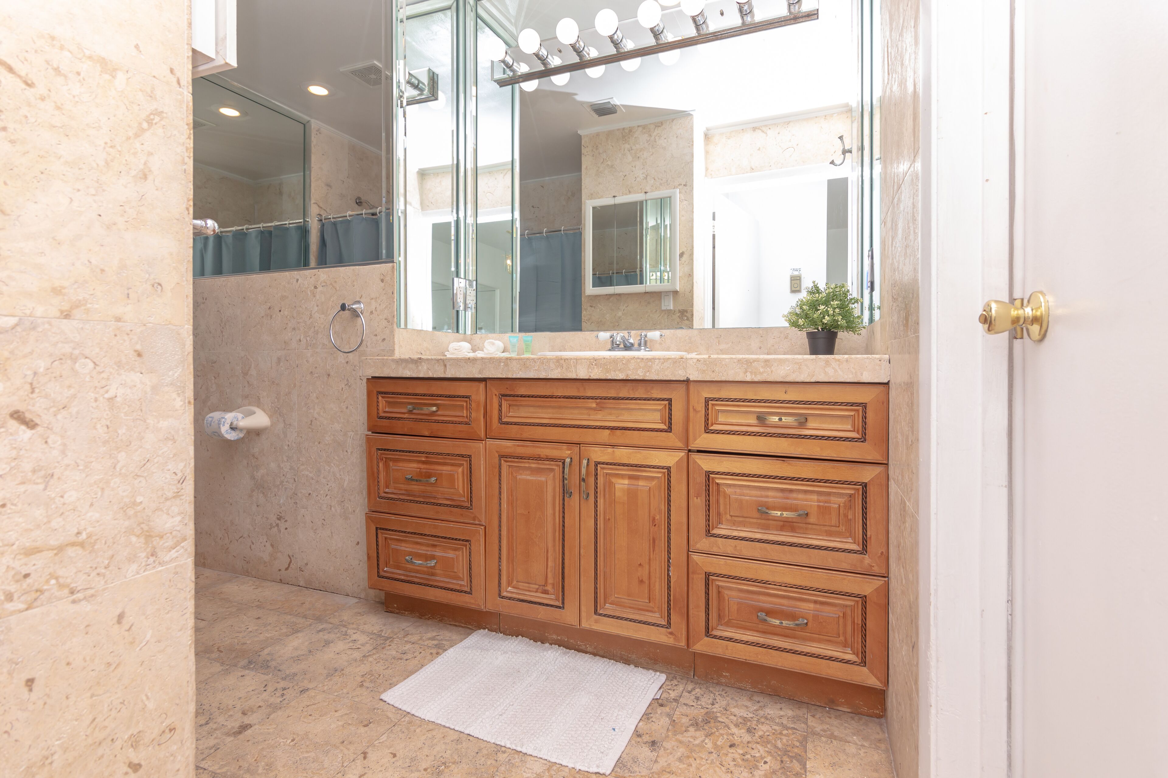 A bathroom with wooden cabinets, a mirror, and a shower area.