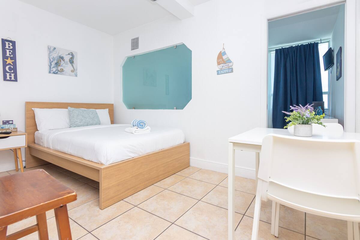 Quarto com cama de madeira, uma escrivaninha e uma cadeira.