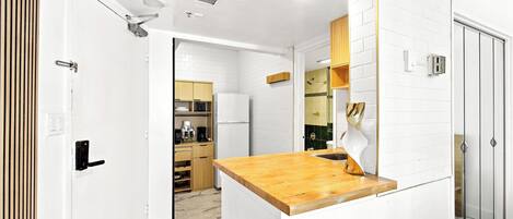 A modern kitchen with white cabinetry, a wooden countertop, and a glass-enclosed shower area.