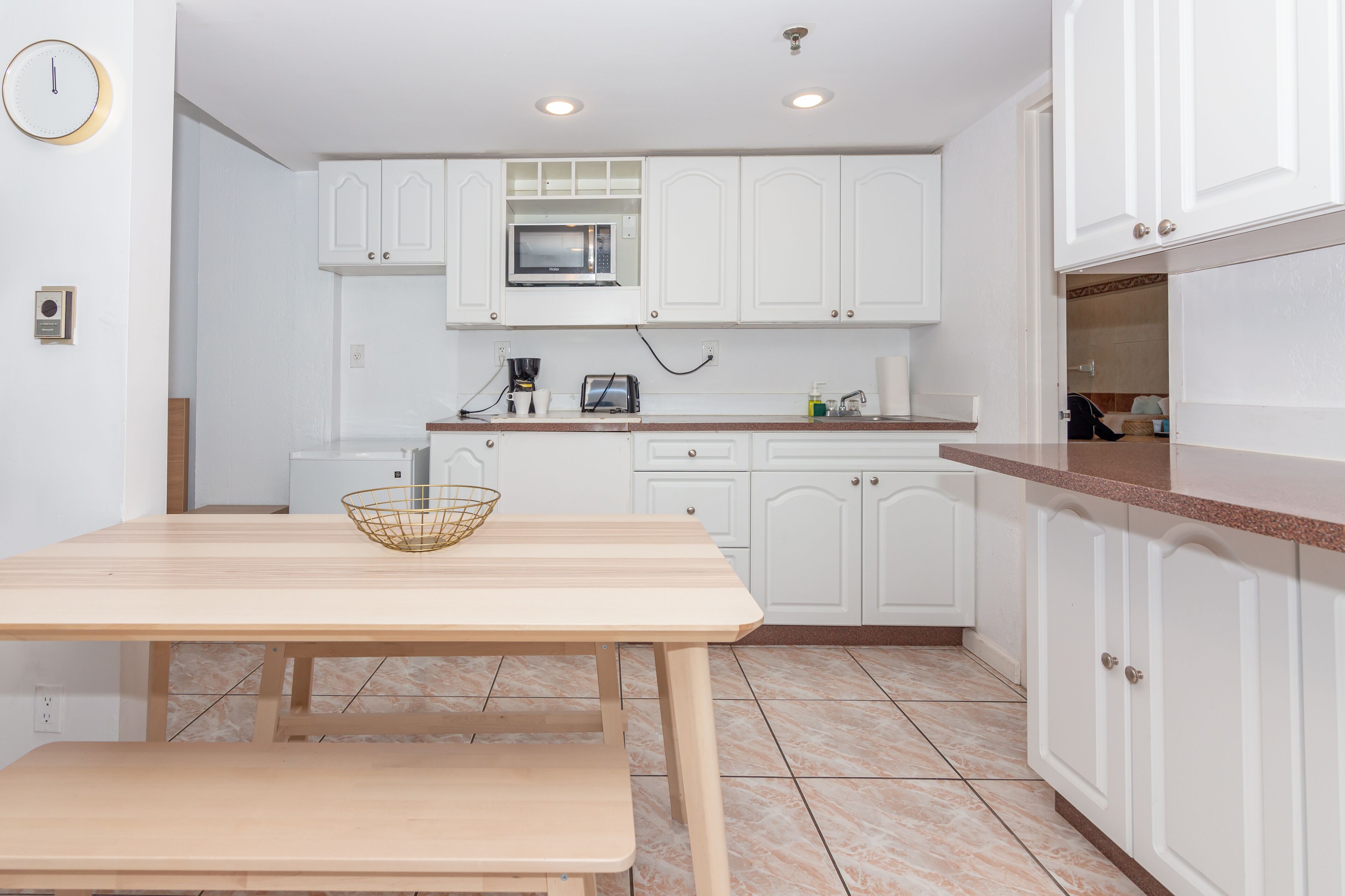 Una cocina moderna con armarios blancos, una mesa de madera y un microondas integrado.