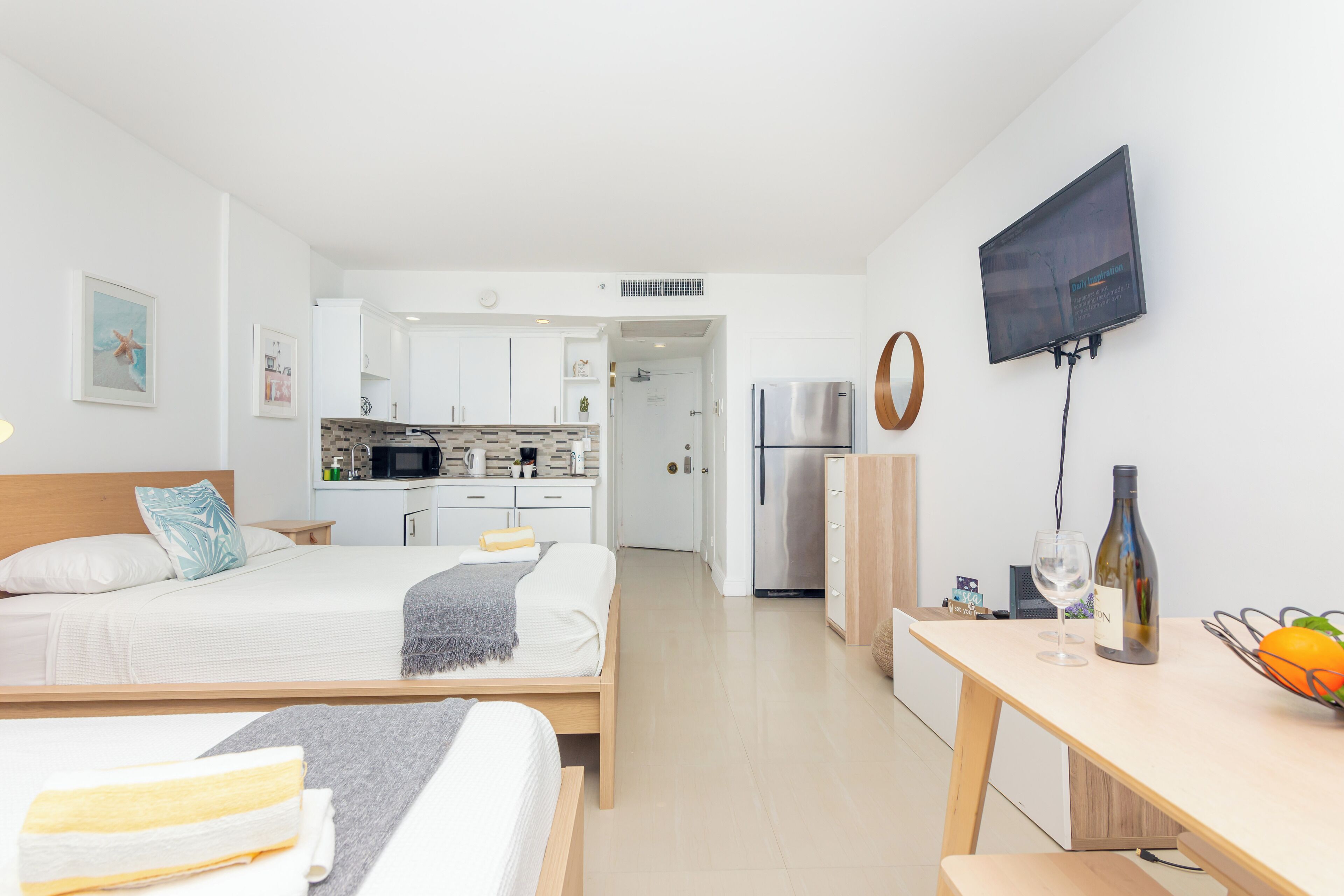 Una habitación de hotel moderna con una cama, una mesita de noche y vistas al área de la cocina.