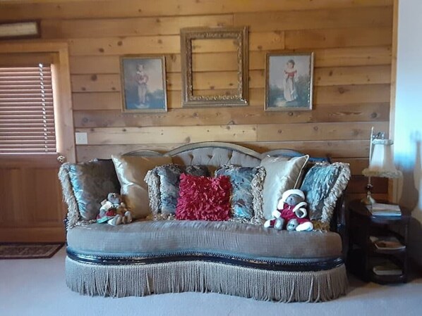 Una sala de estar acogedora con un sofá capitonado, almohadones decorativos y obras de arte enmarcadas en la pared.