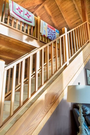 Una escalera de madera con barandilla que sube a un piso superior.