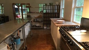 Una cocina con una estufa grande, encimeras de acero inoxidable y una variedad de utensilios y utensilios de cocina en estantes.