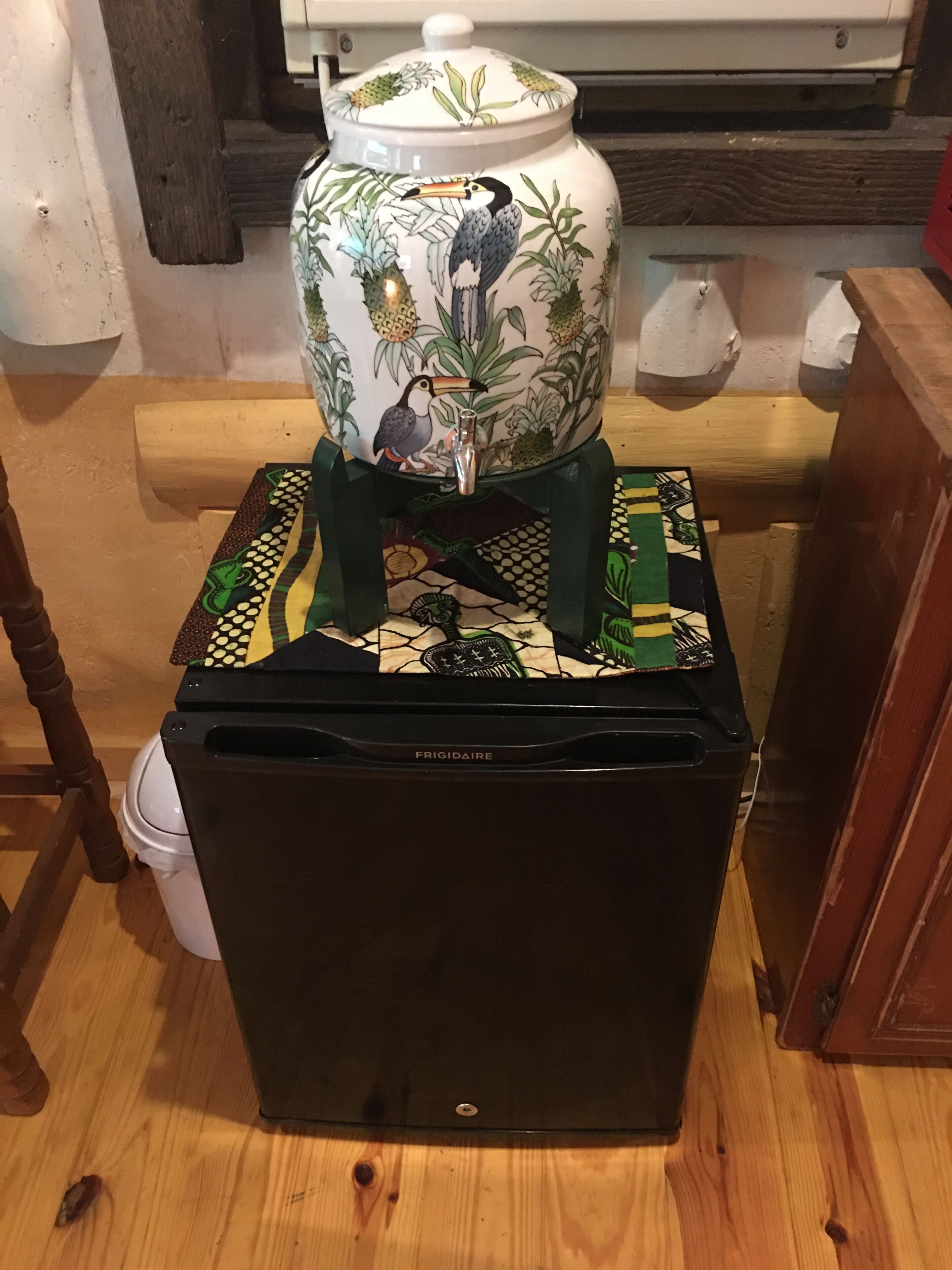 Een zwarte koelkast met een decoratieve keramieken pot erop.