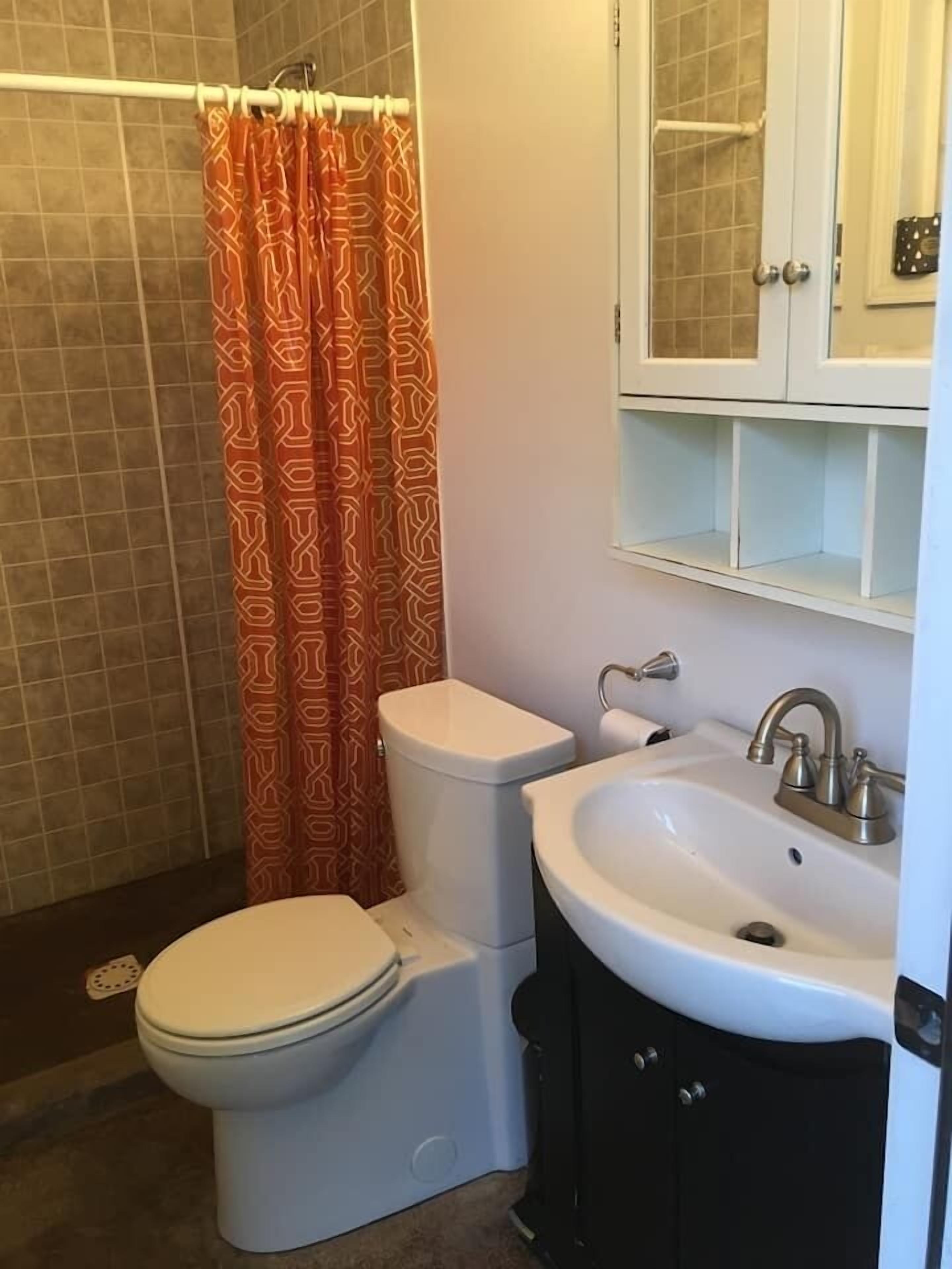 Een badkamer met toilet, wastafel en douchegordijn.