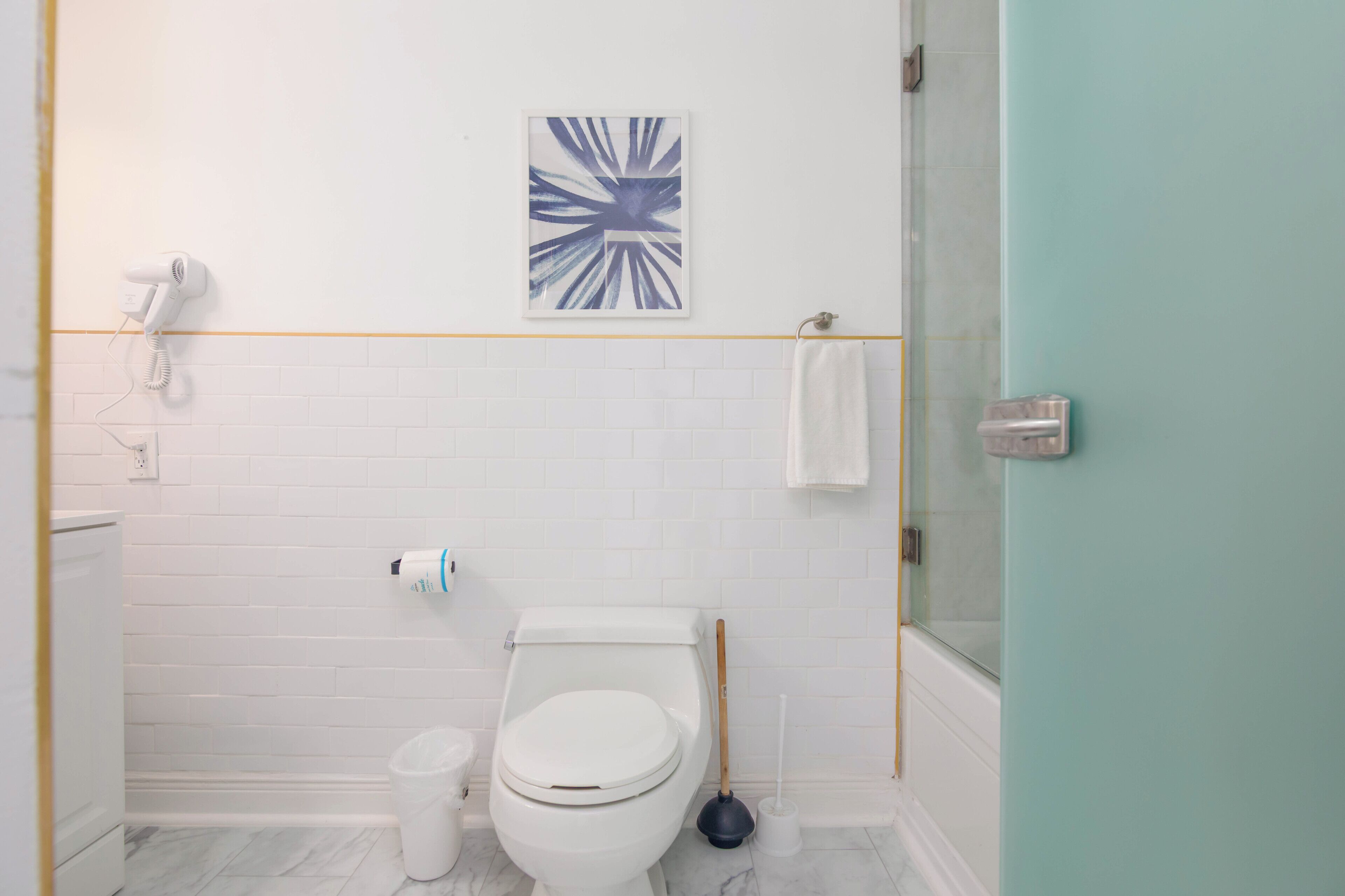 A bathroom with a white toilet, a white sink, a white shower, and a glass-enclosed shower area.
