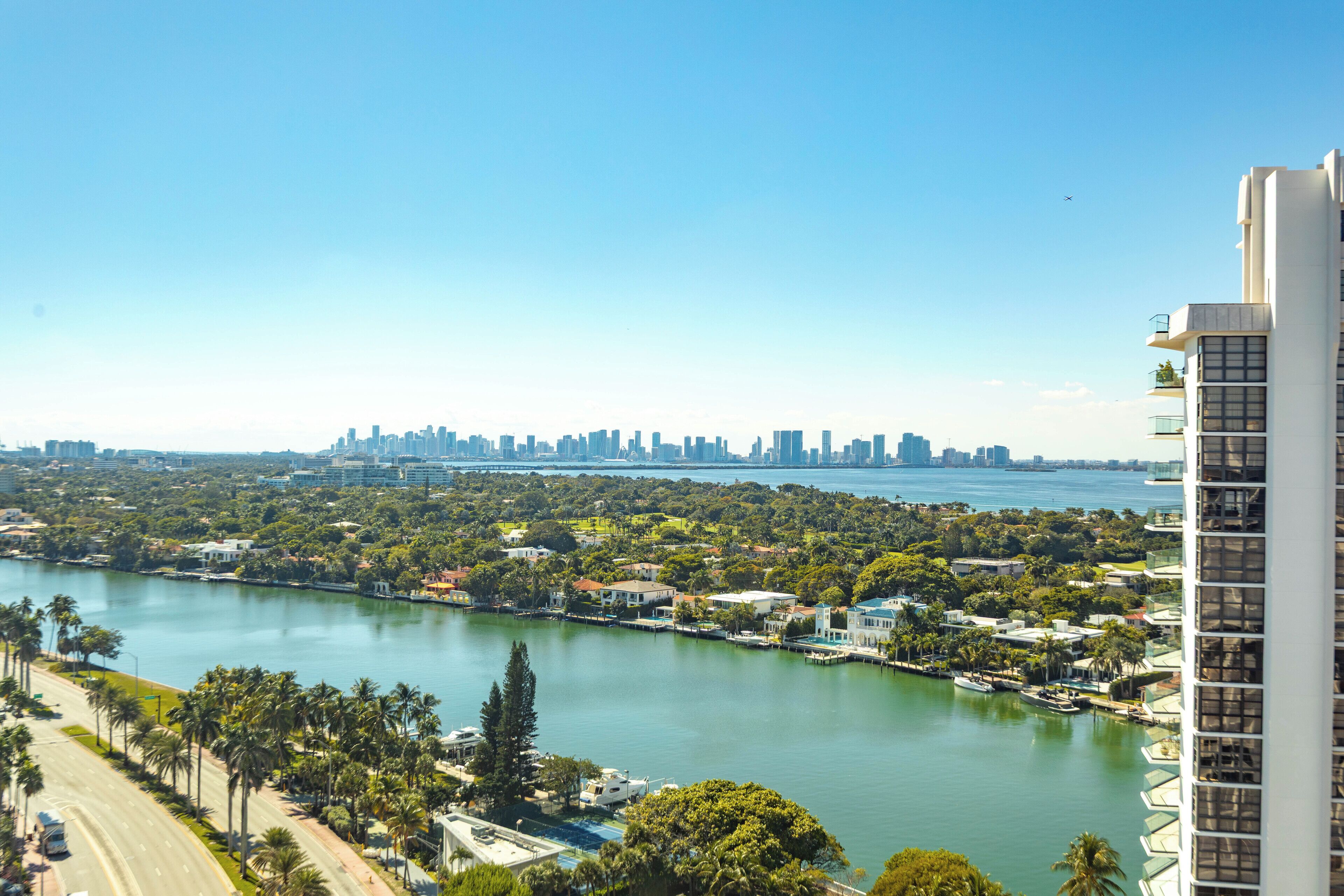 A high-rise hotel overlooking a body of water with a city skyline in the background.