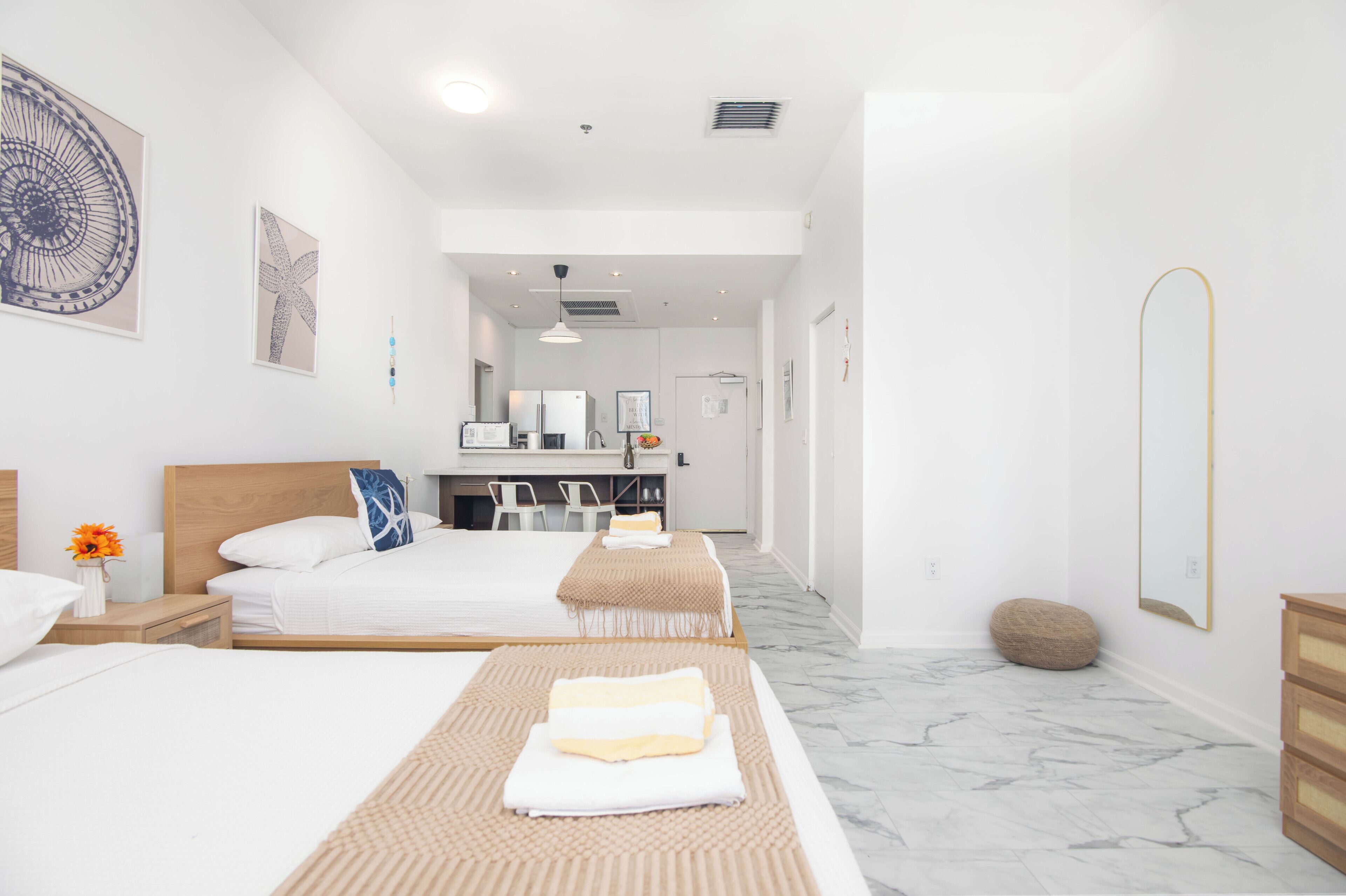 Una habitación de hotel con dos camas, zona de estar, kitchenette y baño.